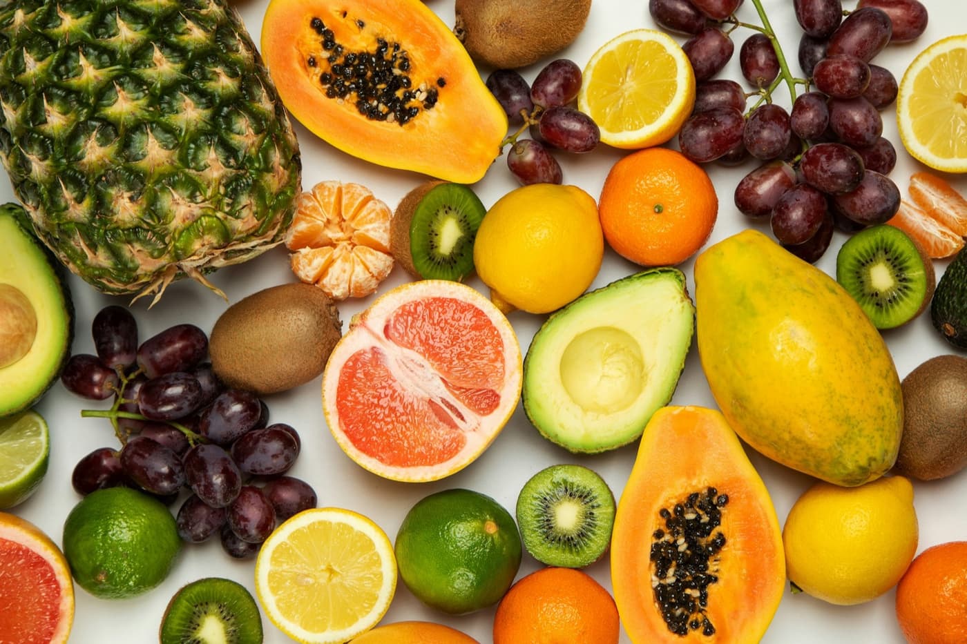 A premium flat-lay of fresh seasonal fruits including citrus, grapes, kiwi and berries